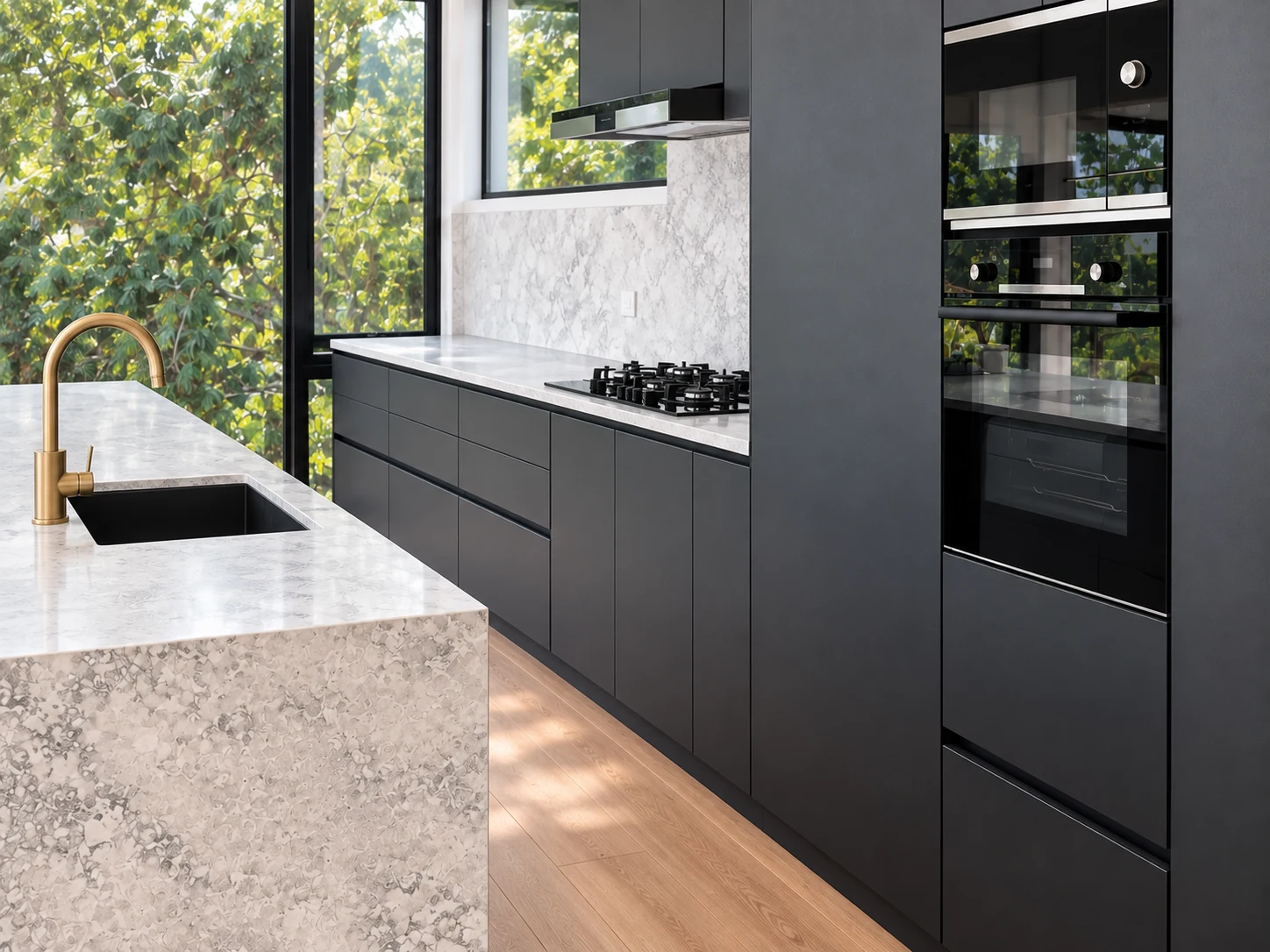 Charcoal cabinetry with integrated ovens, a stone island and garden views