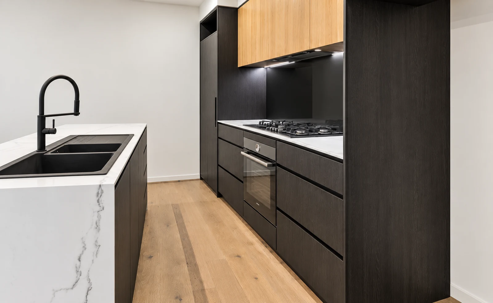 Charcoal galley kitchen with oak upper cabinets and a white stone island