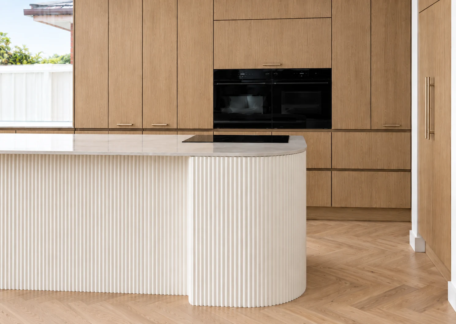 Natural oak cabinetry with a curved ivory fluted island
