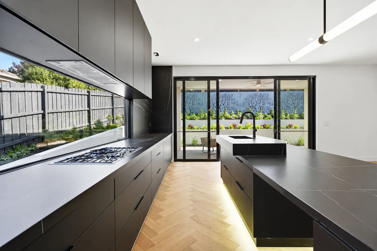Dark kitchen cabinetry with a black island and warm herringbone flooring