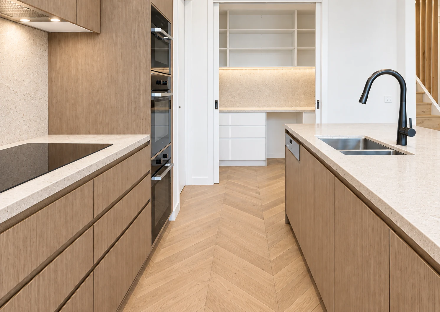 Natural oak galley kitchen with a black tap and a bright walk-in pantry