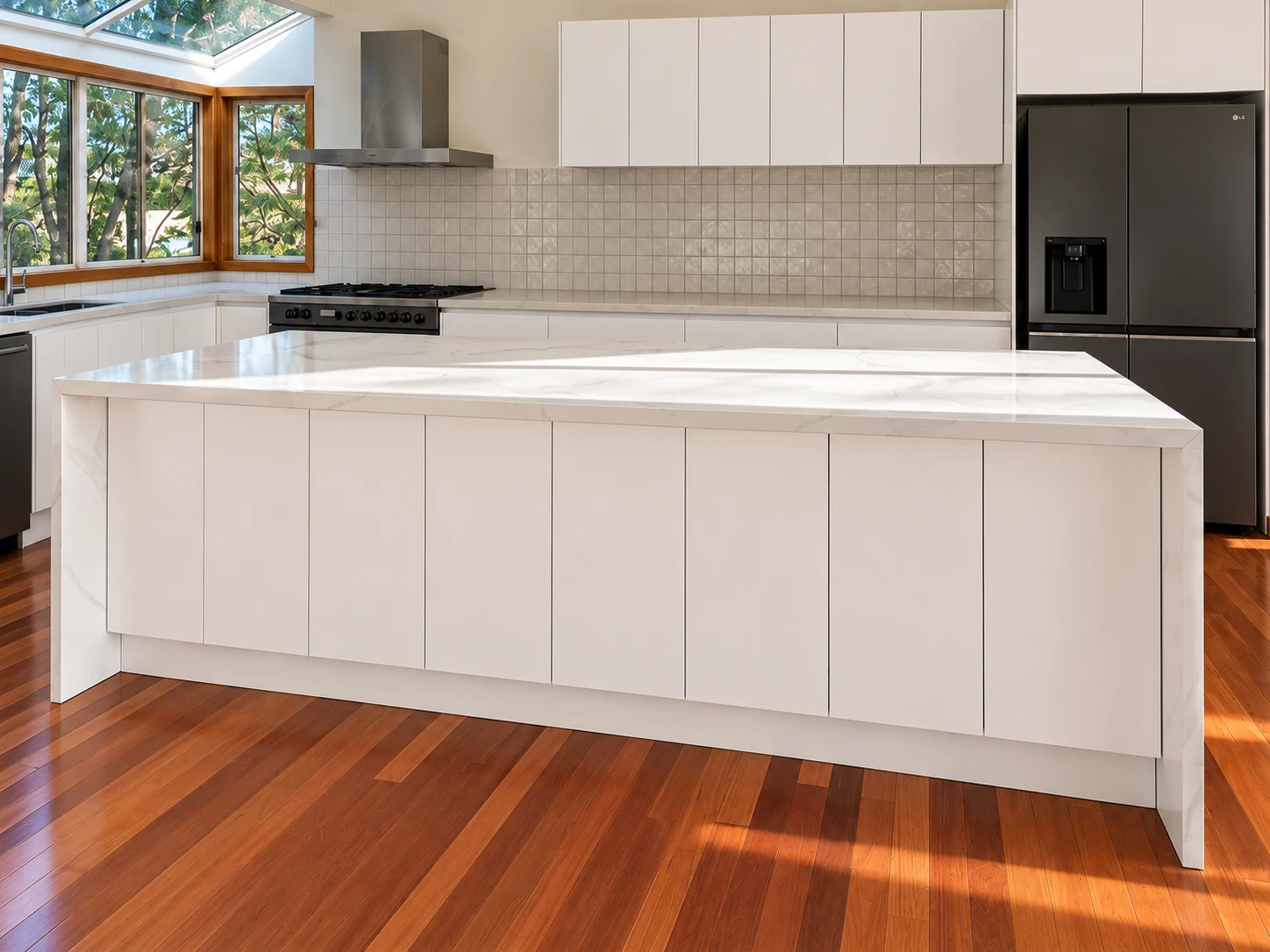 Sunlit white kitchen with timber flooring and a broad island