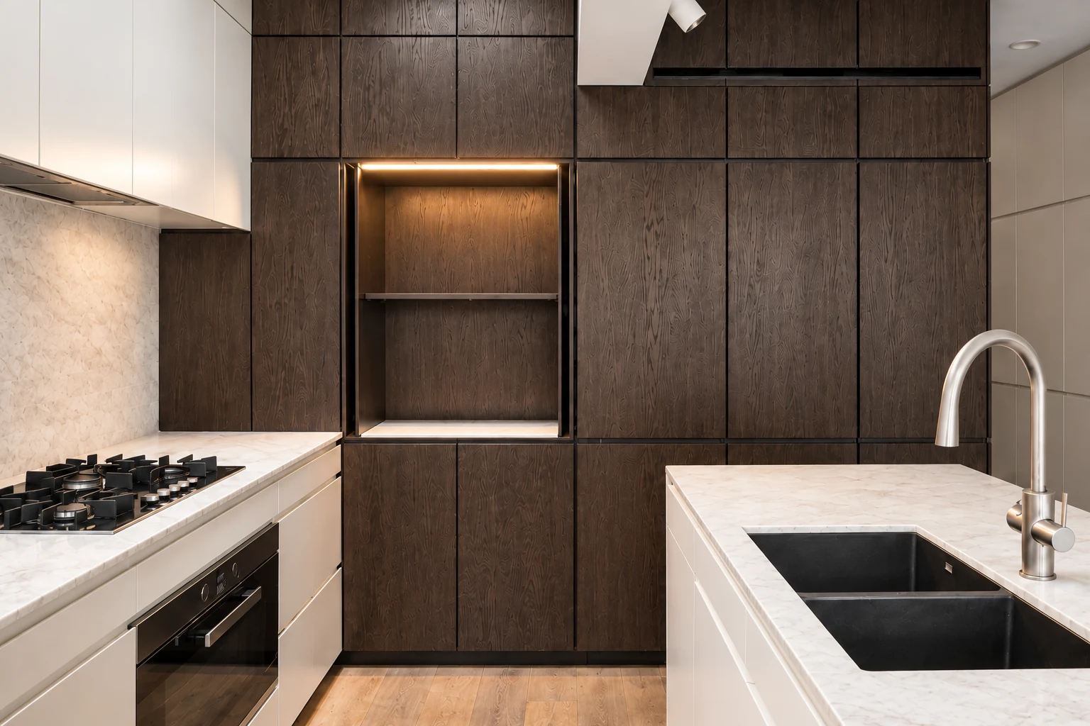 Dark walnut cabinetry with an illuminated display niche and pale worktops