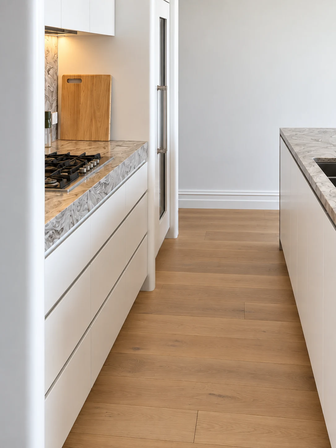 White kitchen cabinetry and stone worktops along a narrow walkway