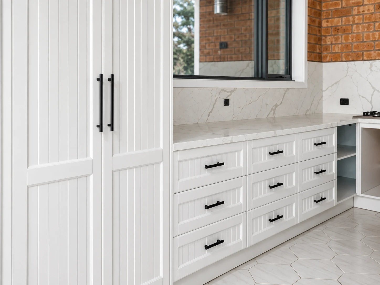 White shaker cabinetry with black handles and stone worktops