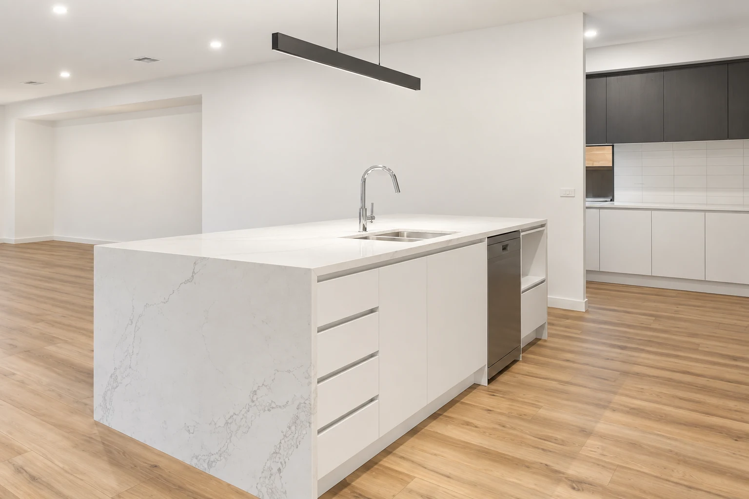 White waterfall island with drawers and an integrated dishwasher