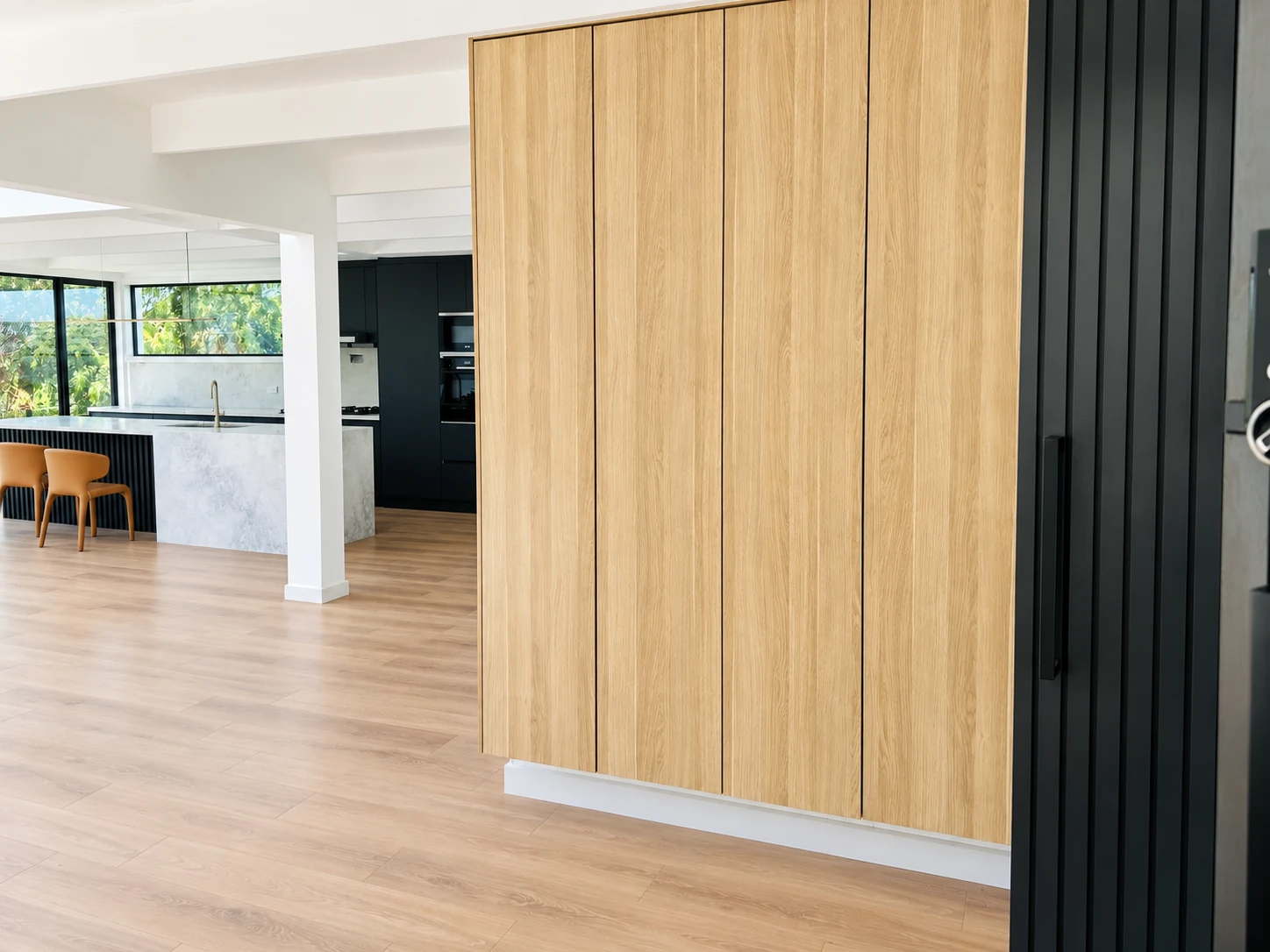 Four-door oak entryway storage cabinet beside a black slatted partition