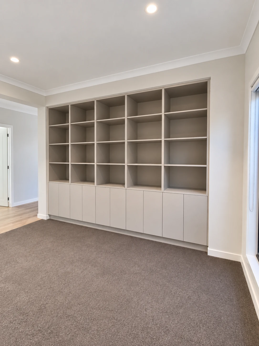 Warm grey built-in bookcase with open shelving and enclosed base cabinets