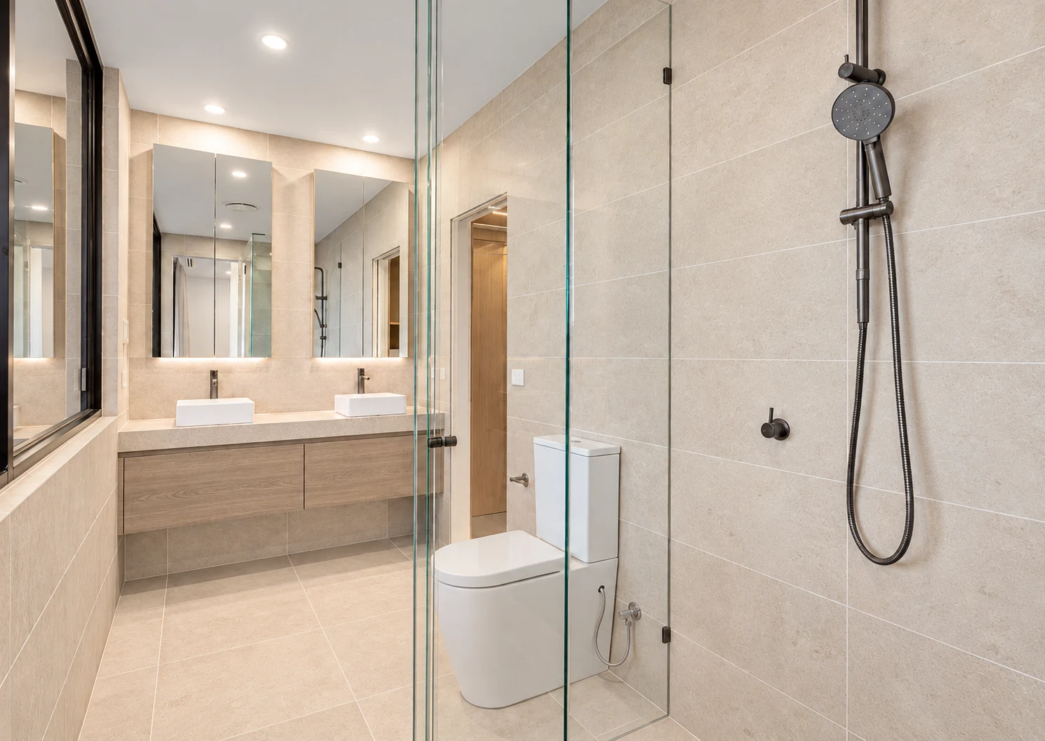 Smoked oak double vanity with warm beige tiles in a compact ensuite